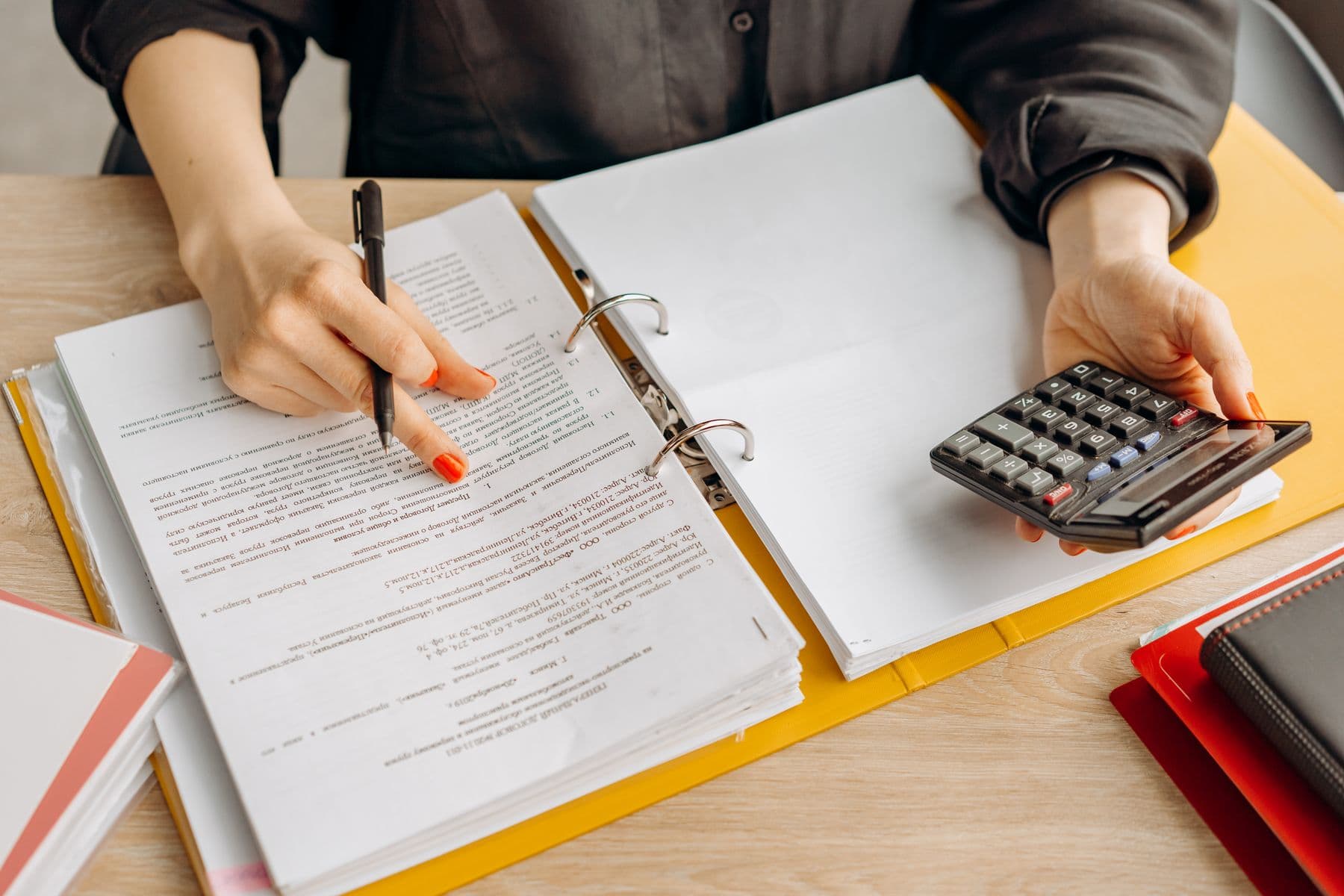 A man working through papers with a calculator at a desk