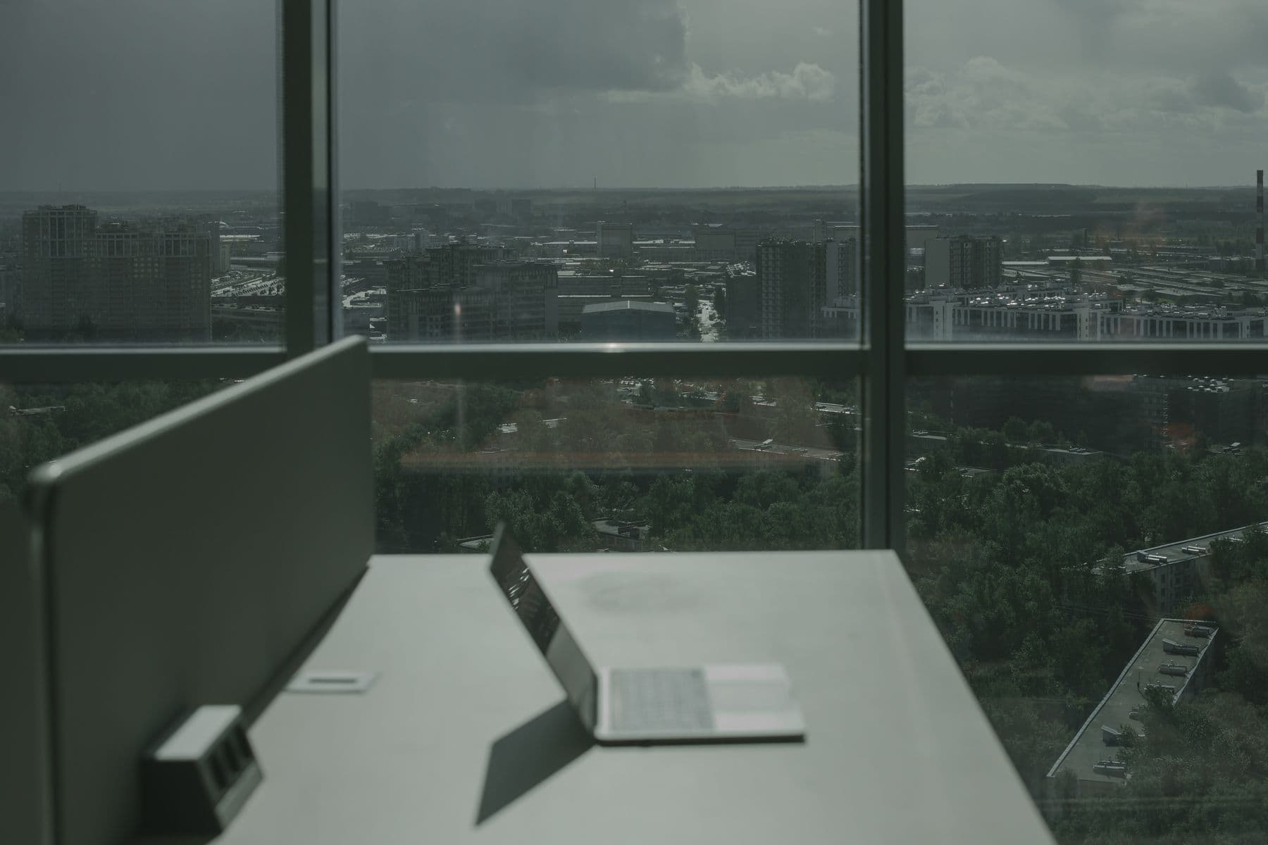 An office desk by a window with a laptop and papers